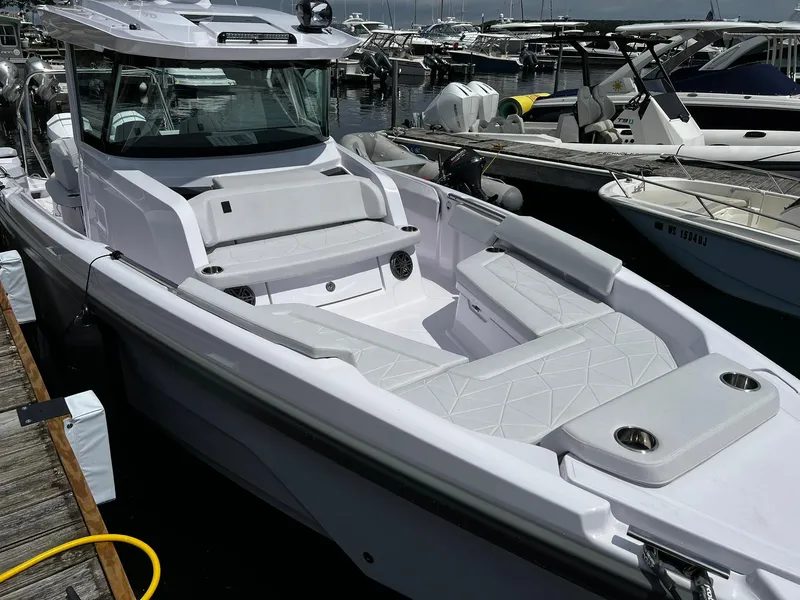 Slide: The Image of 2025 Axopar 29 CCX boat docked, featuring sleek white seating and modern design. - 2