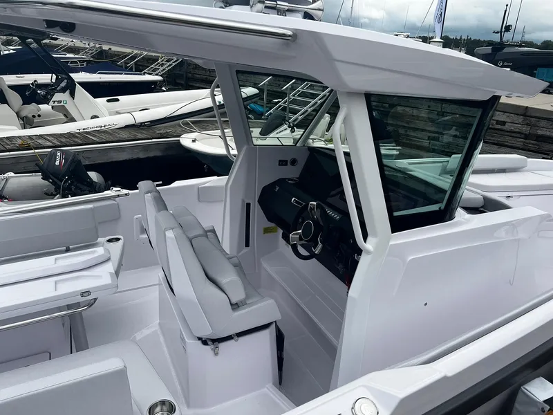 Slide: The Image of 2025 Axopar 29 CCX boat interior with modern helm and seating at a marina. - 6