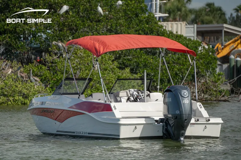 Slide: The Image of 2024 Starcraft SVX 210 OB DC boat with red canopy on water. - 3