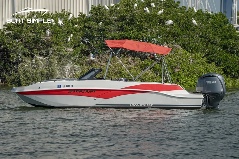 Slide: The Image of 2024 Starcraft SVX 210 OB DC boat with red canopy on water. - 1