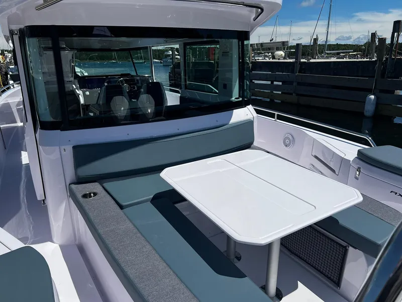 Slide: The Image of 2025 Axopar 37 XC CROSS CABIN boat with outdoor seating and table, docked at marina. - 11