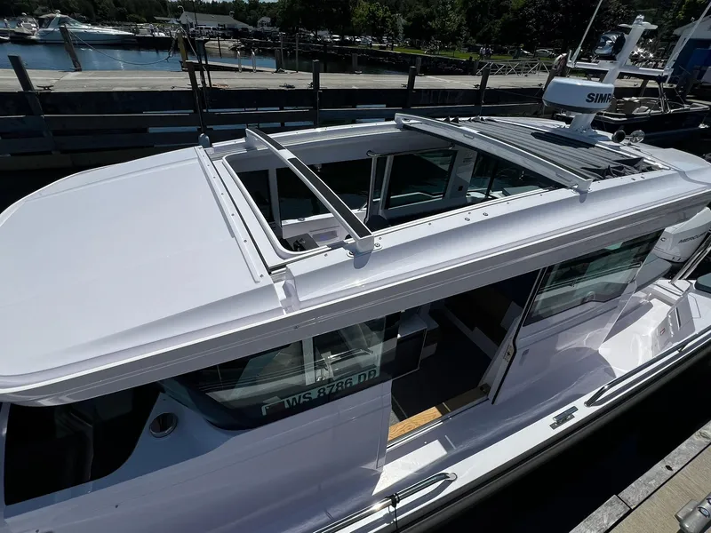 Slide: The Image of 2025 Axopar 37 XC CROSS CABIN boat docked, featuring sleek design and open sunroof. - 12