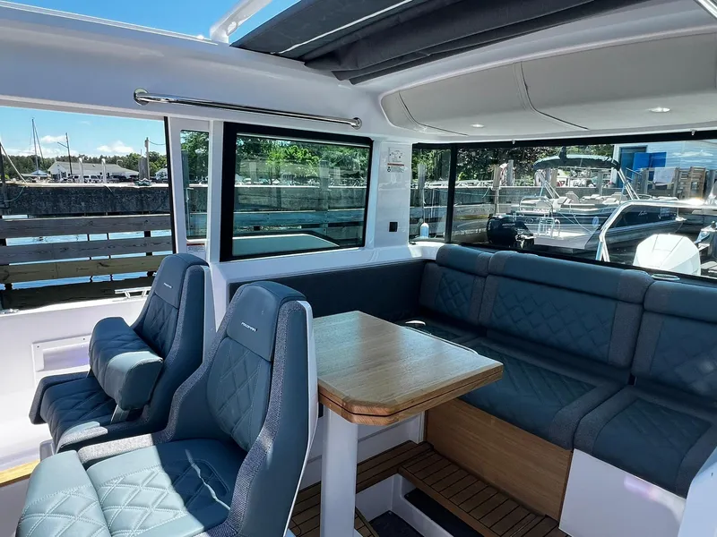 Slide: The Image of 2025 Axopar 37 XC CROSS CABIN interior with blue seating and wooden table. - 17