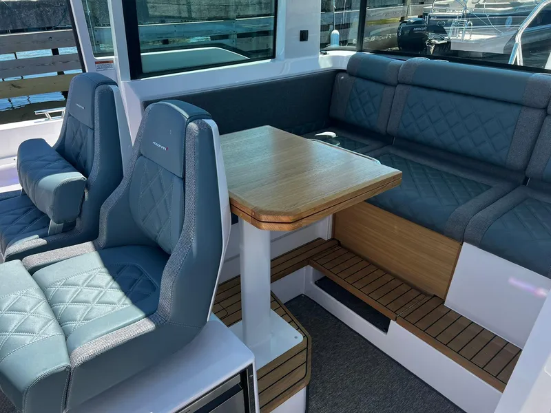 Slide: The Image of 2025 Axopar 37 XC CROSS CABIN interior with blue seating and wooden table. - 18