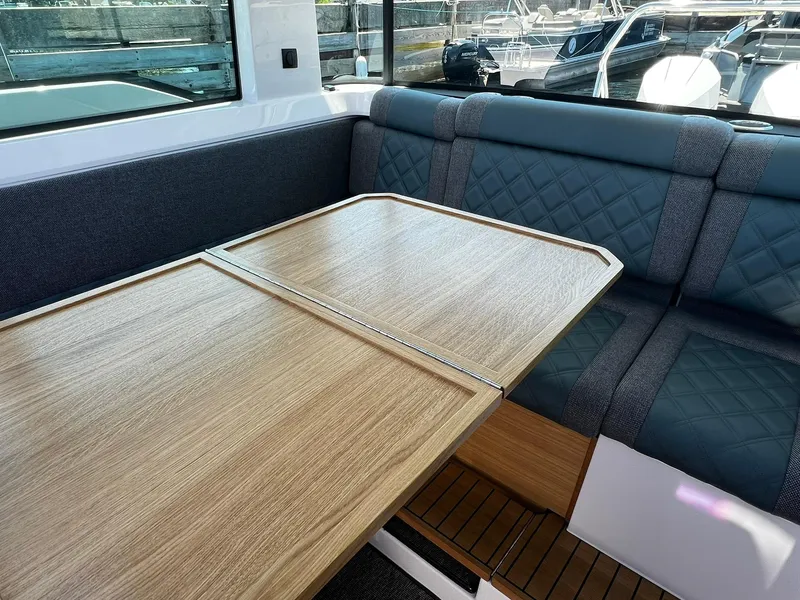 Slide: The Image of Interior of 2025 Axopar 37 XC CROSS CABIN with wooden table and cushioned seating. - 19