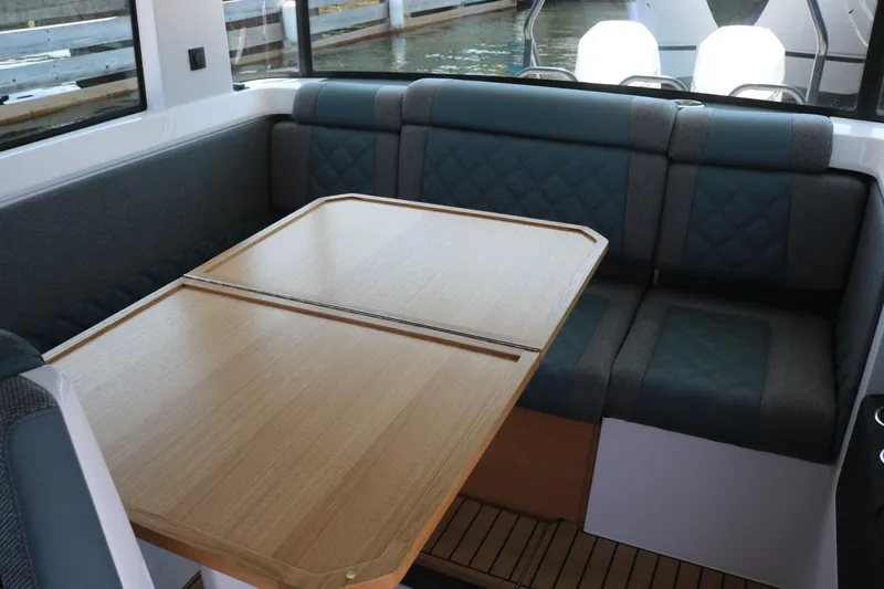 Slide: The Image of Interior of 2025 Axopar 37 XC Cross Cabin with wooden table and cushioned seating. - 17