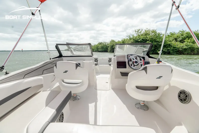 Slide: The Image of 2024 Starcraft SVX 210 OB DC boat interior with dual consoles and seating on a lake. - 5