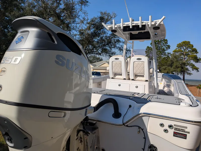 Slide: The Image of 2020 Blue Wave 2800 Makaira boat with Suzuki engine, docked near trees and water. - 13