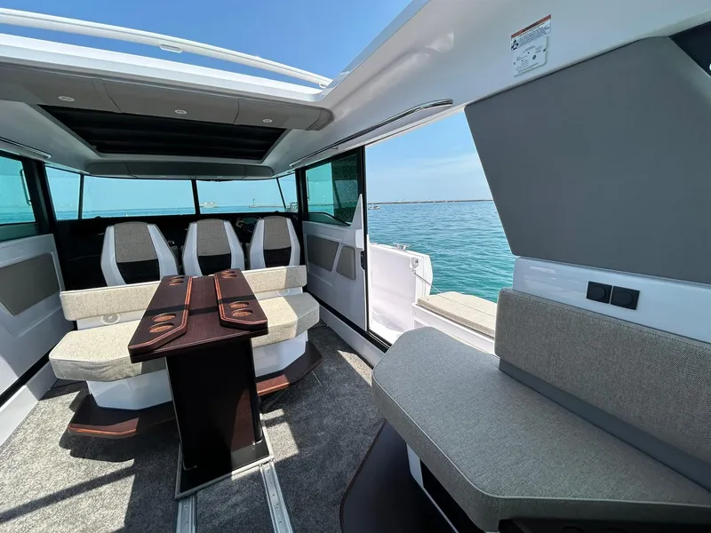 Slide: The Image of 2025 Axopar 45 XC Cross Cabin interior with seating and table, overlooking the ocean. - 18