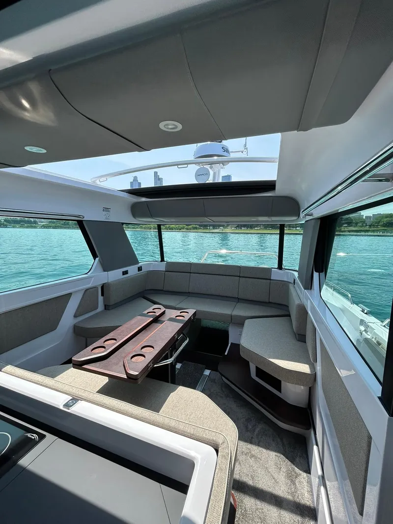Slide: The Image of Interior of 2025 Axopar 45 XC Cross Cabin with seating and table, overlooking water. - 20