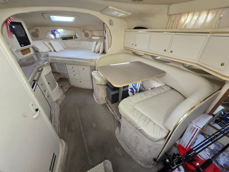 Slide: The Image of Interior of 2000 Sea Ray 310 Sundancer, featuring cozy seating and compact dining area. - 2