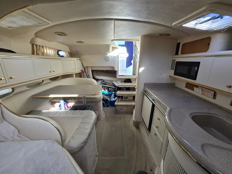 Slide: The Image of Interior of a 2000 Sea Ray 310 Sundancer boat, featuring a kitchenette and seating area. - 24