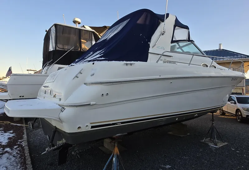 Slide: The Image of 2000 Sea Ray 310 Sundancer boat on stands, covered, in a marina setting. - 5