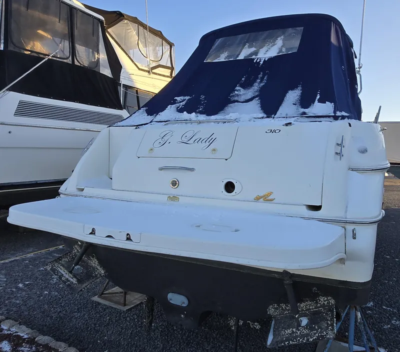 Slide: The Image of 2000 Sea Ray 310 Sundancer boat with snow-covered cover, docked outdoors. - 7