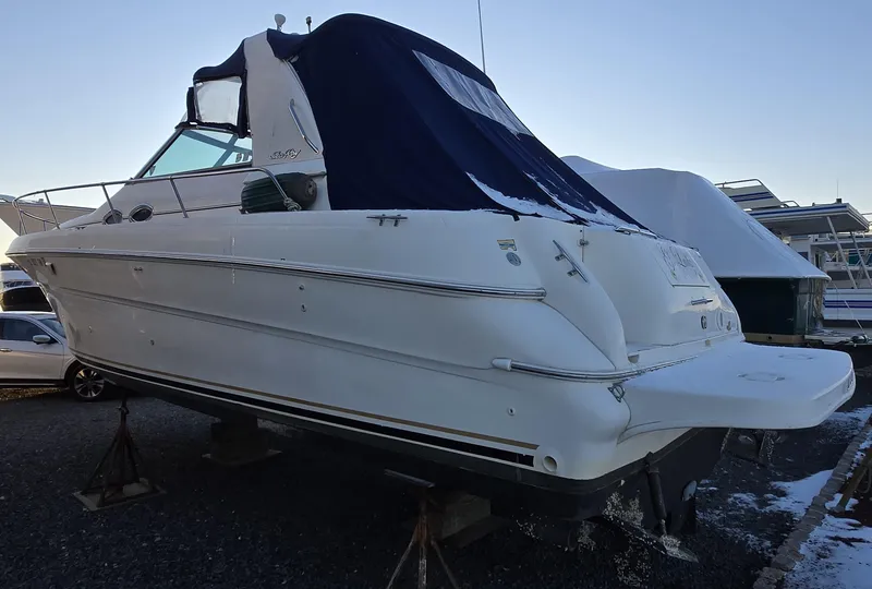 Slide: The Image of 2000 Sea Ray 310 Sundancer boat on stands, covered, in a marina setting. - 8