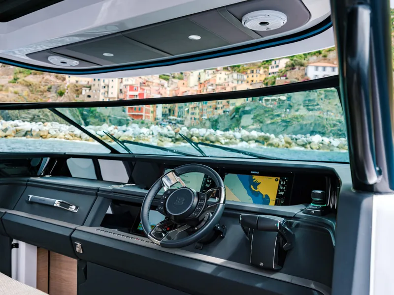 Slide: The Image of 2025 Axopar 45 SUN TOP helm with modern dashboard and scenic coastal view. - 11