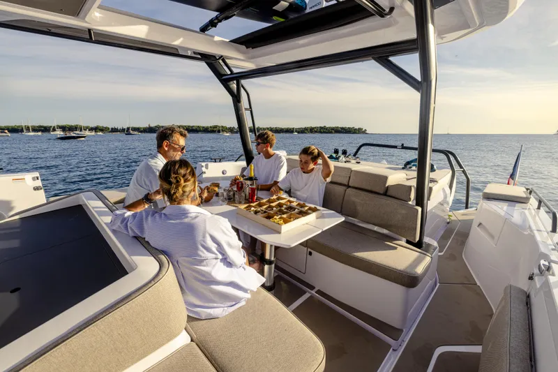 Slide: The Image of Family enjoying a meal on a 2025 Axopar 45 SUN TOP boat. - 13