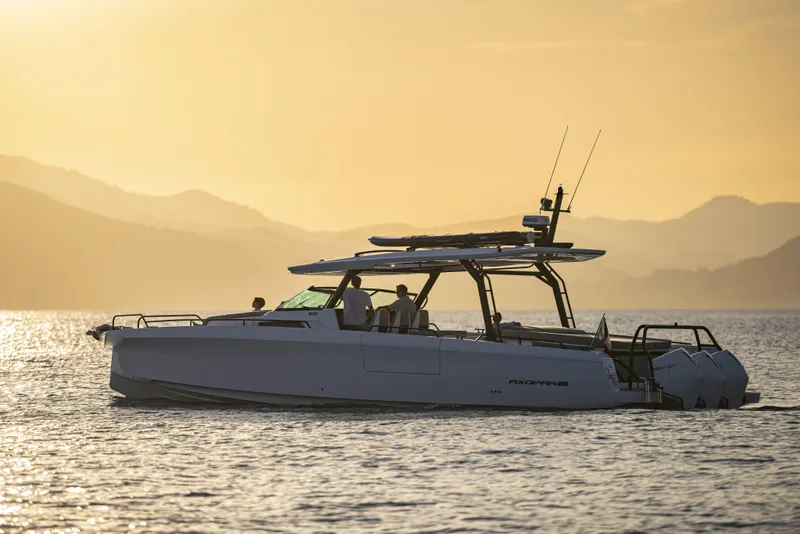 Slide: The Image of 2025 Axopar 45 SUN TOP boat on water at sunset, mountains in background. - 5