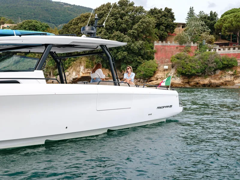 Slide: The Image of 2025 Axopar 45 SUN TOP yacht cruising near scenic coastline. - 9