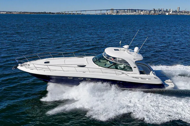 Slide: The Image of 2005 Sea Ray 500 Sundancer yacht cruising on open water with city skyline in background. - 6