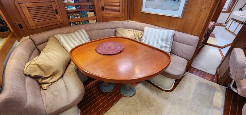 Slide: The Image of Cozy dining area in a 1995 Catalina 42 MkII sailboat with cushioned seating and wooden table. - 18