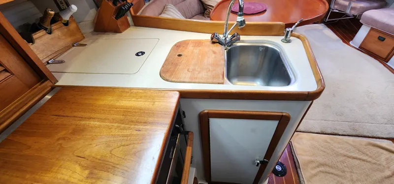 Slide: The Image of Interior of 1995 Catalina 42 MkII yacht, featuring a compact kitchen with sink and wooden cabinetry. - 28