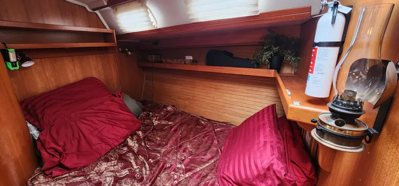 Slide: The Image of Cozy cabin interior of a 1995 Catalina 42 MkII sailboat with red bedding and wooden finish. - 31