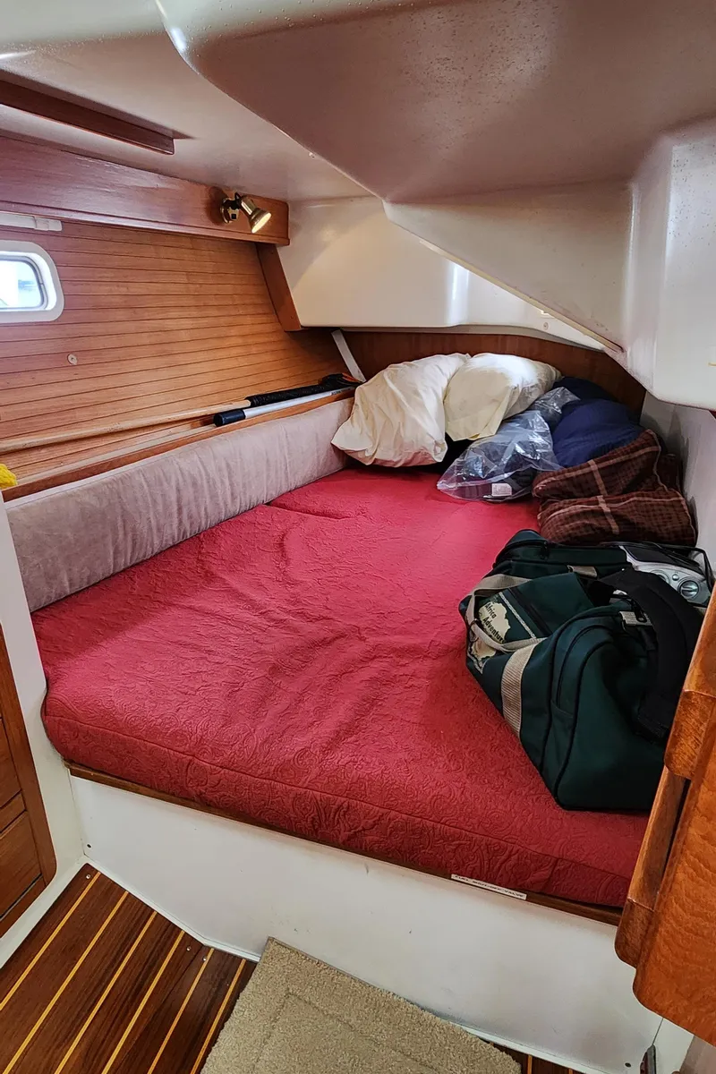 Slide: The Image of Cozy cabin interior of a 1995 Catalina 42 MkII sailboat with red bedding and wooden accents. - 42