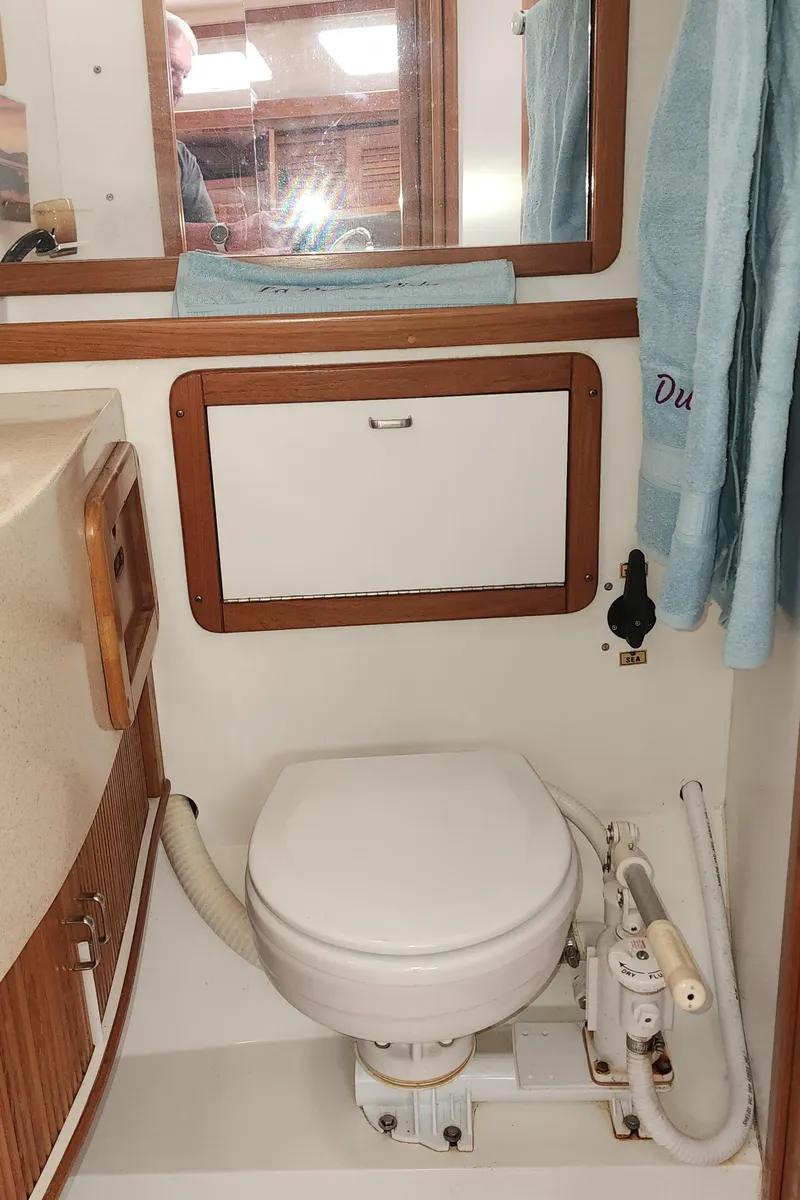 Slide: The Image of 1995 Catalina 42 MkII yacht bathroom with toilet, wooden accents, and mirror. - 44