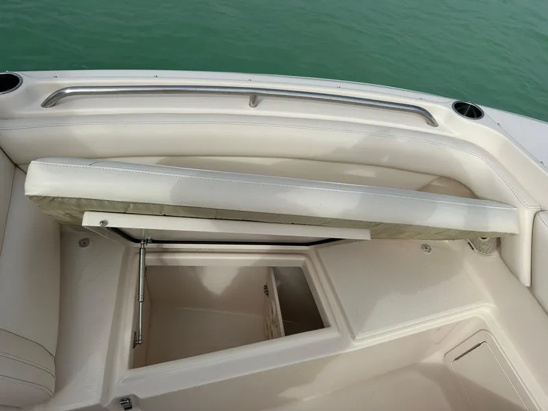 Slide: The Image of 2018 Grady-White Freedom 275 boat storage compartment with open hatch, white interior, and green water background. - 17