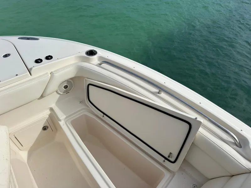 Slide: The Image of 2018 Grady-White Freedom 275 boat storage compartment, open, with view of turquoise water. - 19