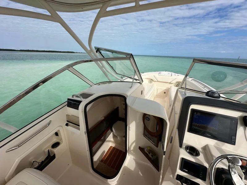 Slide: The Image of 2018 Grady-White Freedom 275 boat interior with ocean view, featuring helm and cabin entrance. - 24