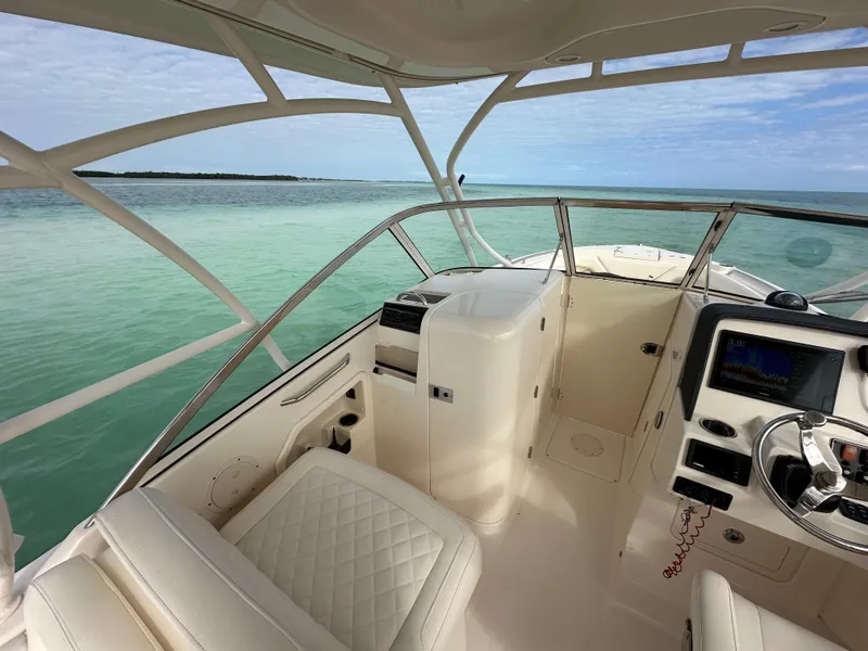 Slide: The Image of 2018 Grady-White Freedom 275 boat interior with ocean view, featuring helm and seating area. - 26