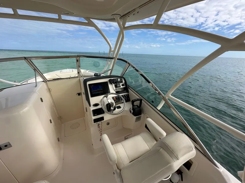 Slide: The Image of 2018 Grady-White Freedom 275 boat interior with steering wheel, ocean view, and clear sky. - 28