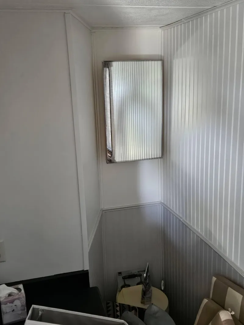 Slide: The Image of Interior of a 1990 Skipperliner houseboat with white paneled walls and a small window. - 13