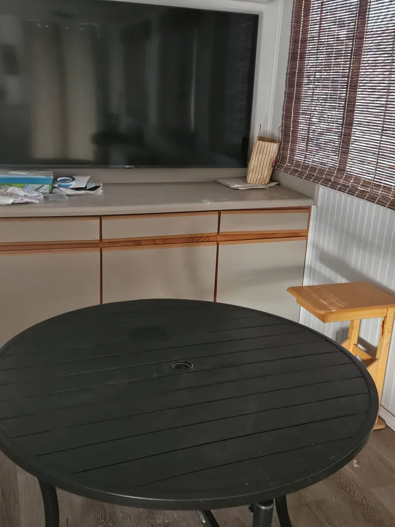 Slide: The Image of Interior of a 1990 Skipperliner houseboat with a round table and TV. - 4