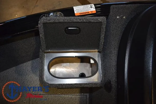 Slide: The Image of 2024 Lund 1775 Impact XS Sport boat storage compartment with open lid, featuring carpeted interior. - 21