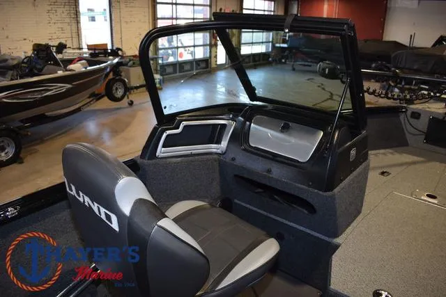 Slide: The Image of 2024 Lund 1775 Impact XS Sport boat interior with seating and dashboard in showroom. - 26