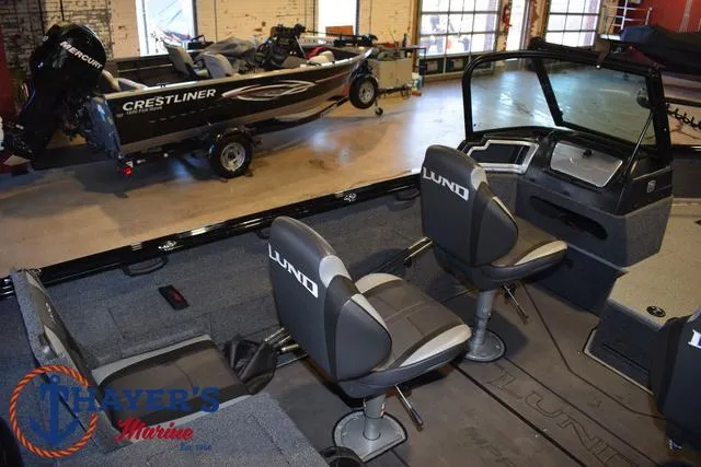 Slide: The Image of 2024 Lund 1775 Impact XS Sport boat interior with seating and dashboard in showroom. - 27