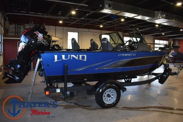 Slide: The Image of 2024 Lund 1775 Impact XS Sport boat in showroom, blue exterior, on trailer. - 37
