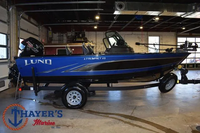 Slide: The Image of 2024 Lund 1775 Impact XS Sport boat in showroom, blue and black design, on trailer. - 38