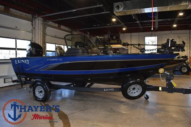 Slide: The Image of 2024 Lund 1775 Impact XS Sport boat in showroom, blue and black design, on trailer. - 39