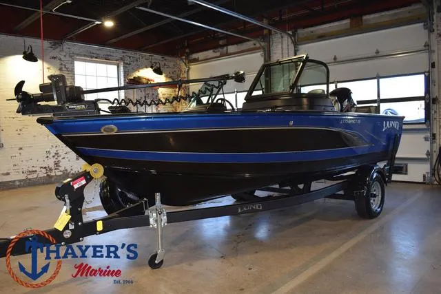 Slide: The Image of 2024 Lund 1775 Impact XS Sport boat in showroom, blue and black design, Thayer's Marine logo. - 6