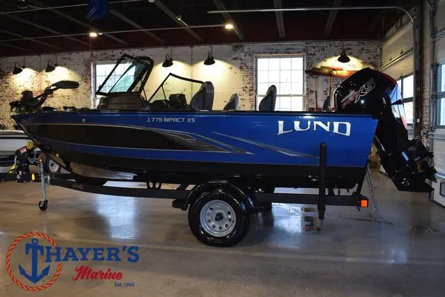 Slide: The Image of 2024 Lund 1775 Impact XS Sport boat in showroom, blue exterior, displayed on trailer. - 8
