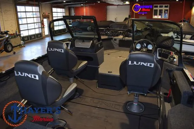 Slide: The Image of 2024 Lund 1775 Impact XS Sport boat interior with seating and dashboard in showroom. - 9