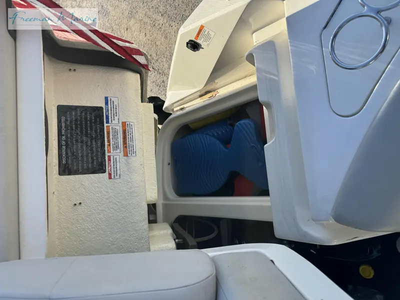 Slide: The Image of 2020 Sea Ray SLX 280 boat storage compartment with safety labels and equipment. - 35