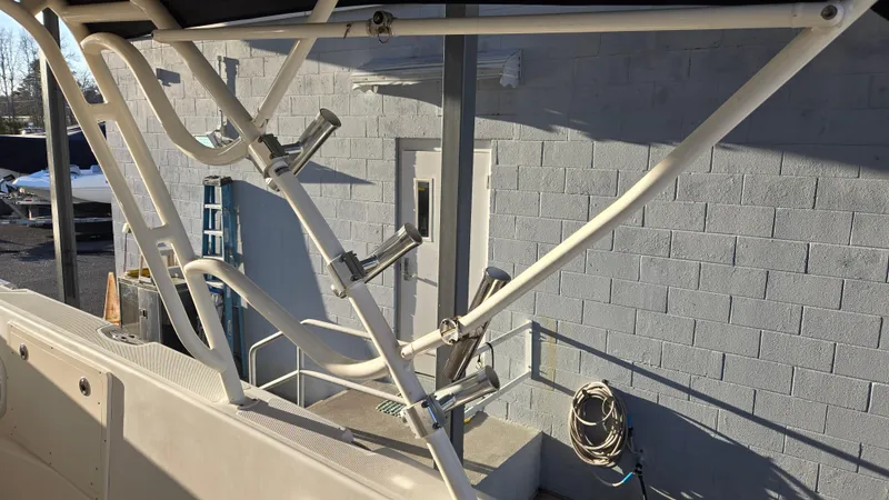 Slide: The Image of 2006 Wellcraft 352 Sport boat with rod holders and ladder, docked near a concrete wall. - 12
