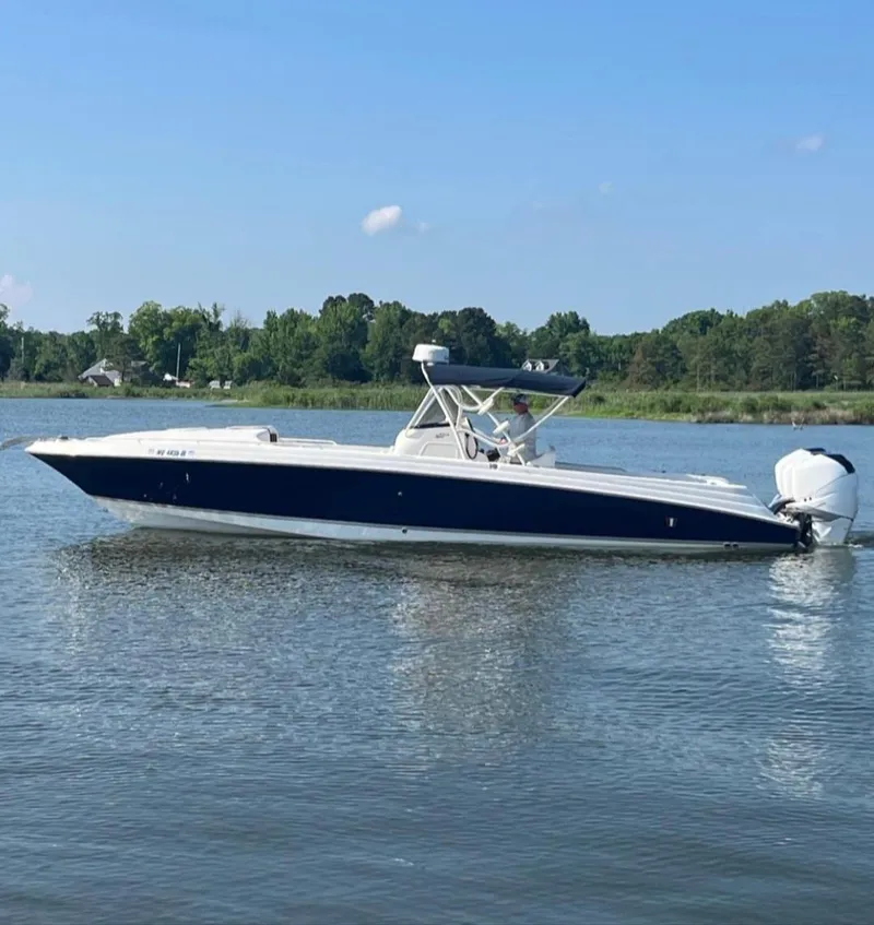 Slide: The Image of 2006 Wellcraft 352 Sport boat on calm water, surrounded by lush greenery. - 2