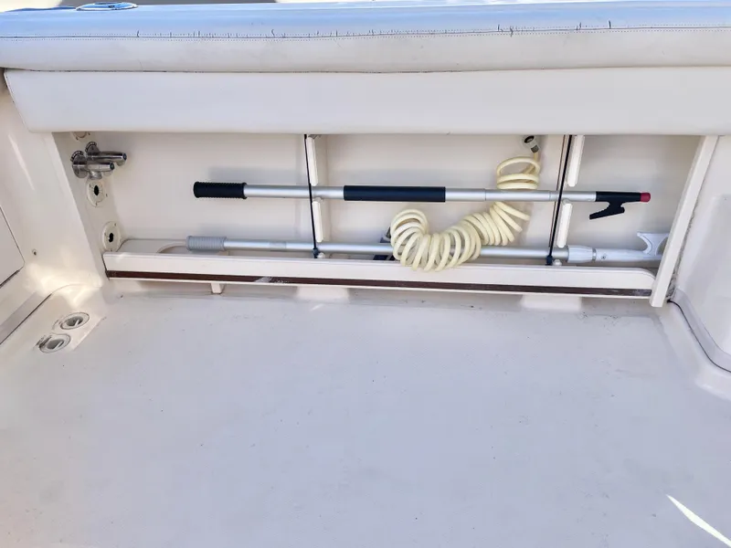 Slide: The Image of 2015 Grady-White Express 330 boat storage compartment with coiled hose and cleaning tools. - 17
