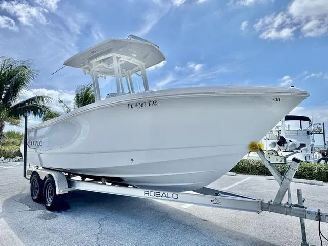 Slide: The Image of 2023 Robalo R230 boat on trailer, parked outdoors under a clear blue sky. - 20